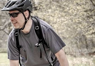 Scott riding a hardtail mountain bike through open spring woodland on the DTE Energy Foundation Trail near Ann Arbor, Michigan